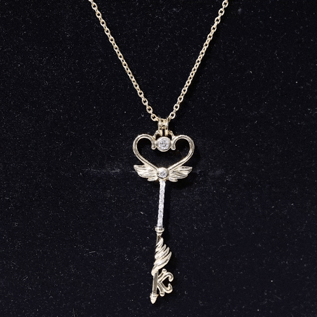 Yellow gold diamond key pendant with angel wings from Rosec Jewels, featuring intricate detailing and elegant design.