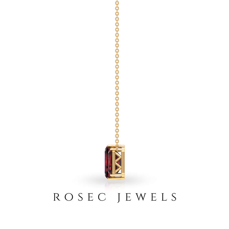 Emerald cut garnet three-stone pendant necklace with rose gold setting, featuring a 2-carat center stone and sparkling side stones.