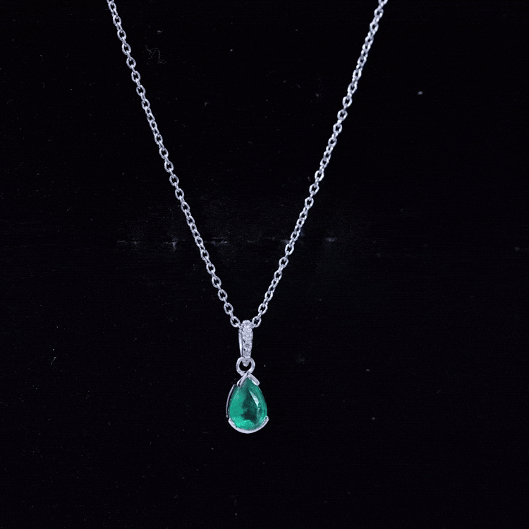 Pear cut emerald solitaire pendant with diamond accent bail from Rosec Jewels, showcasing a green gemstone and elegant silver setting.