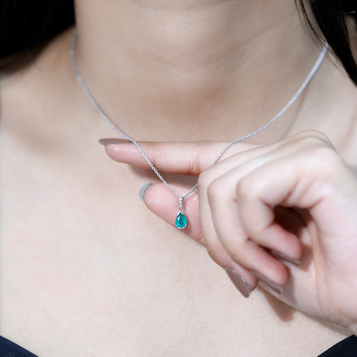 Pear cut emerald solitaire pendant by Rosec Jewels with diamond accent bail, featuring a green emerald gemstone and elegant design.