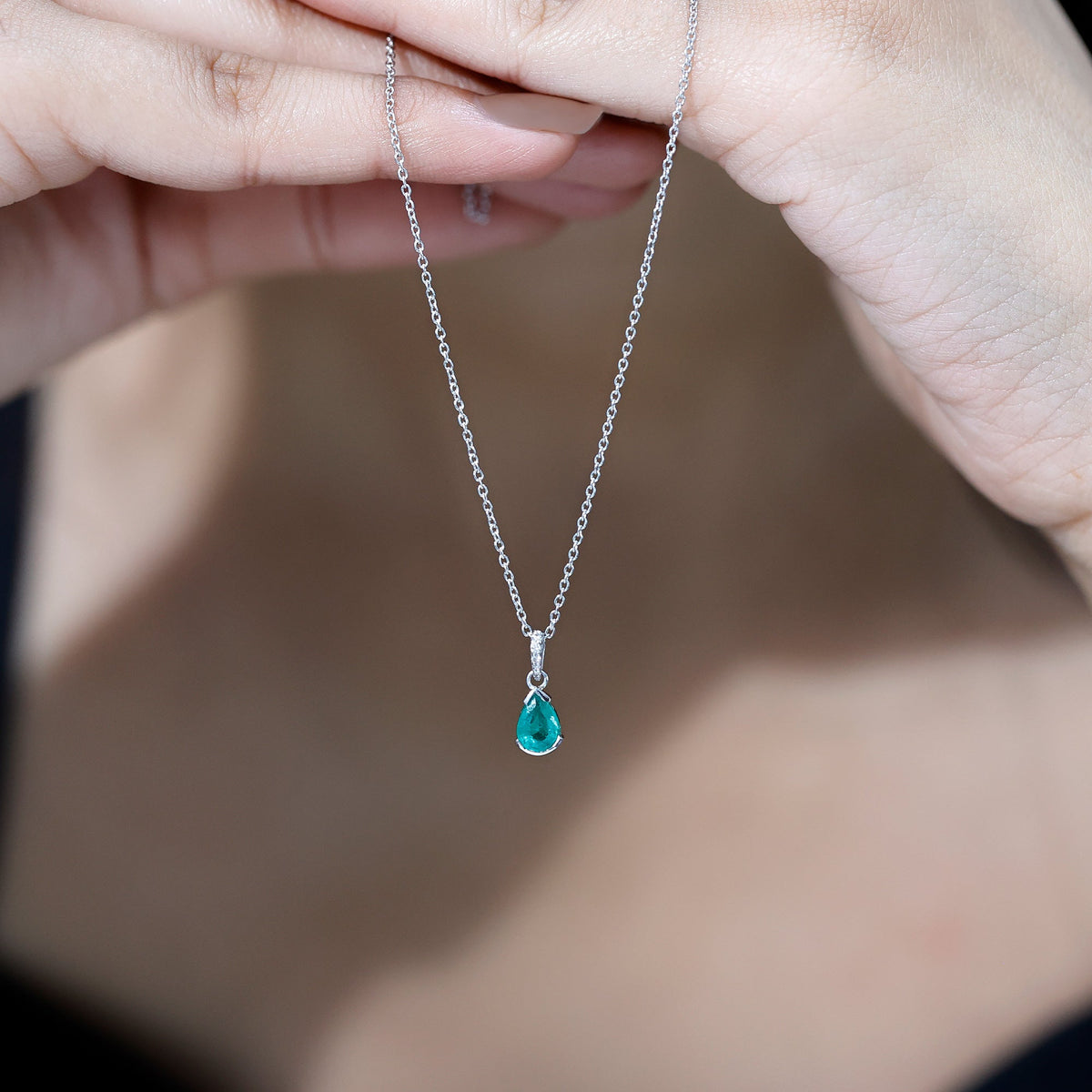 Pear cut emerald solitaire pendant with diamond accent bail showcasing a stunning green gemstone and elegant silver setting.