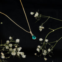 Pear cut emerald solitaire pendant with diamond accent bail by Rosec Jewels, showcasing a elegant green gemstone and sparkling accents.