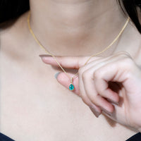 Pear cut emerald solitaire pendant with diamond accent bail from Rosec Jewels, showcasing a elegant green gemstone and sparkling accents.