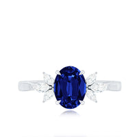Oval lab-grown blue sapphire engagement ring with diamond trio accents, featuring a 1.5 carat gemstone and elegant band design.