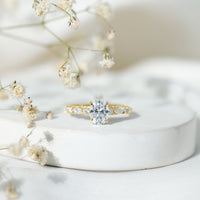 Oval moissanite solitaire engagement ring in claw setting with a rose gold band, showcasing sparkling gemstone and elegant design.