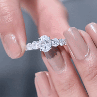 Yellow gold engagement ring with 1.2 carat oval cut moissanite side stones, featuring a detailed band design.