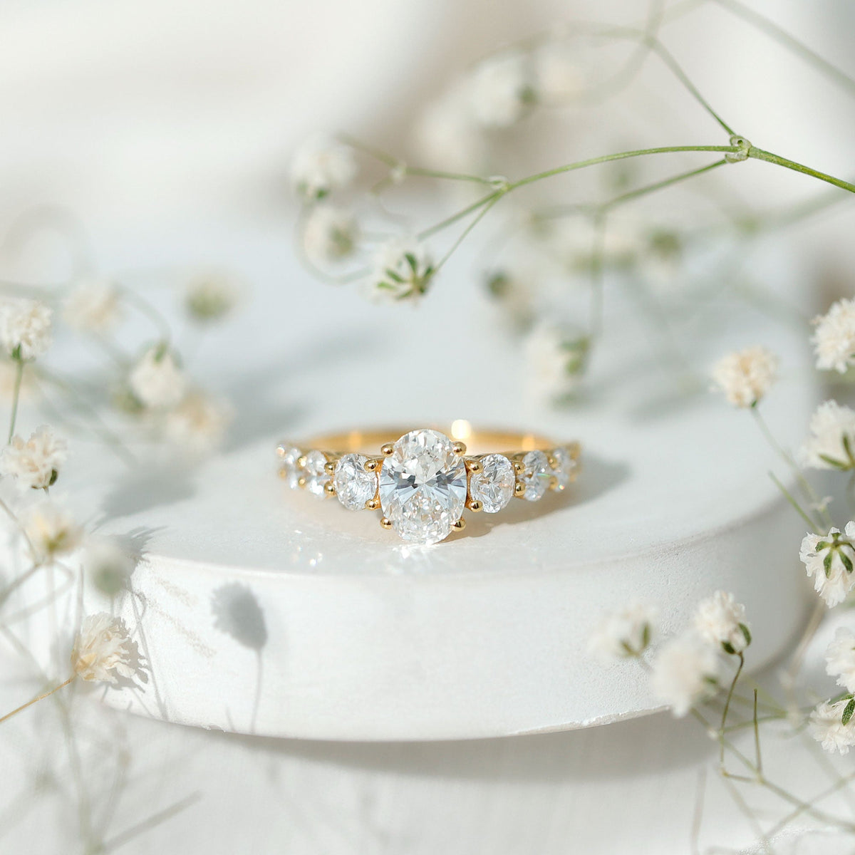Oval cut moissanite side stone engagement ring with a 1.2 carat center, featuring sparkling stones and a polished band from Rosec Jewels.