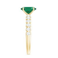 Natural 6x8mm emerald oval engagement ring by Rosec Jewels with diamond side stones, featuring a silver band and intricate design.