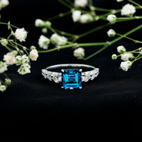 Asscher cut London Blue Topaz solitaire engagement ring with Moissanite, featuring a 3-carat gemstone and rose gold band.