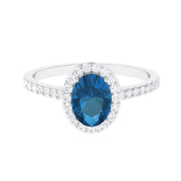 Oval cut London Blue Topaz solitaire ring with diamond halo from Rosec Jewels, showcasing a blue gemstone and sparkling diamond accents.