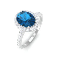 Oval cut London Blue Topaz solitaire ring with diamond halo setting, showcasing a sparkling blue gemstone and intricate band design.