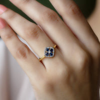 Blue sapphire cluster ring with diamond accents, 1/2 carat total weight, featuring intricate silver band design.