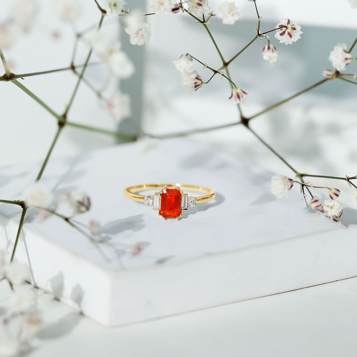Emerald cut fire opal engagement ring with diamonds from Rosec Jewels, showcasing a vibrant orange gemstone and sparkling accents.