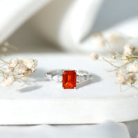 Emerald cut 1 Carat fire opal engagement ring with diamond side stones in rose gold, featuring a sparkling gemstone centerpiece.