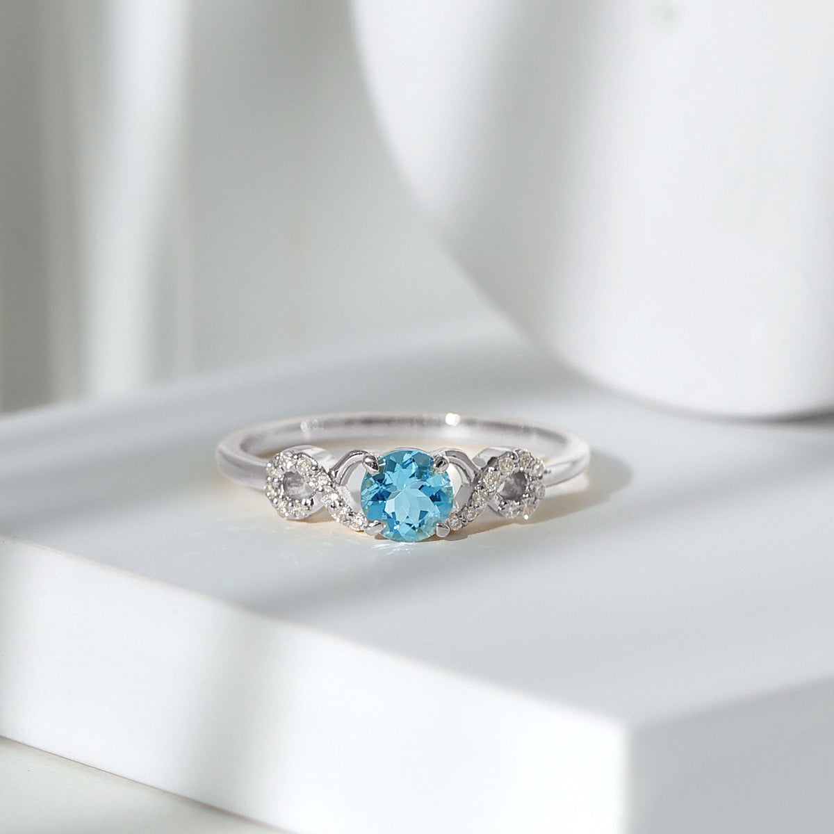 Round aquamarine and diamond infinity engagement ring by Rosec Jewels, showcasing a sparkling center stone with intricate band details.