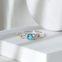 Round aquamarine and diamond infinity engagement ring by Rosec Jewels, showcasing a sparkling center stone with intricate band details.