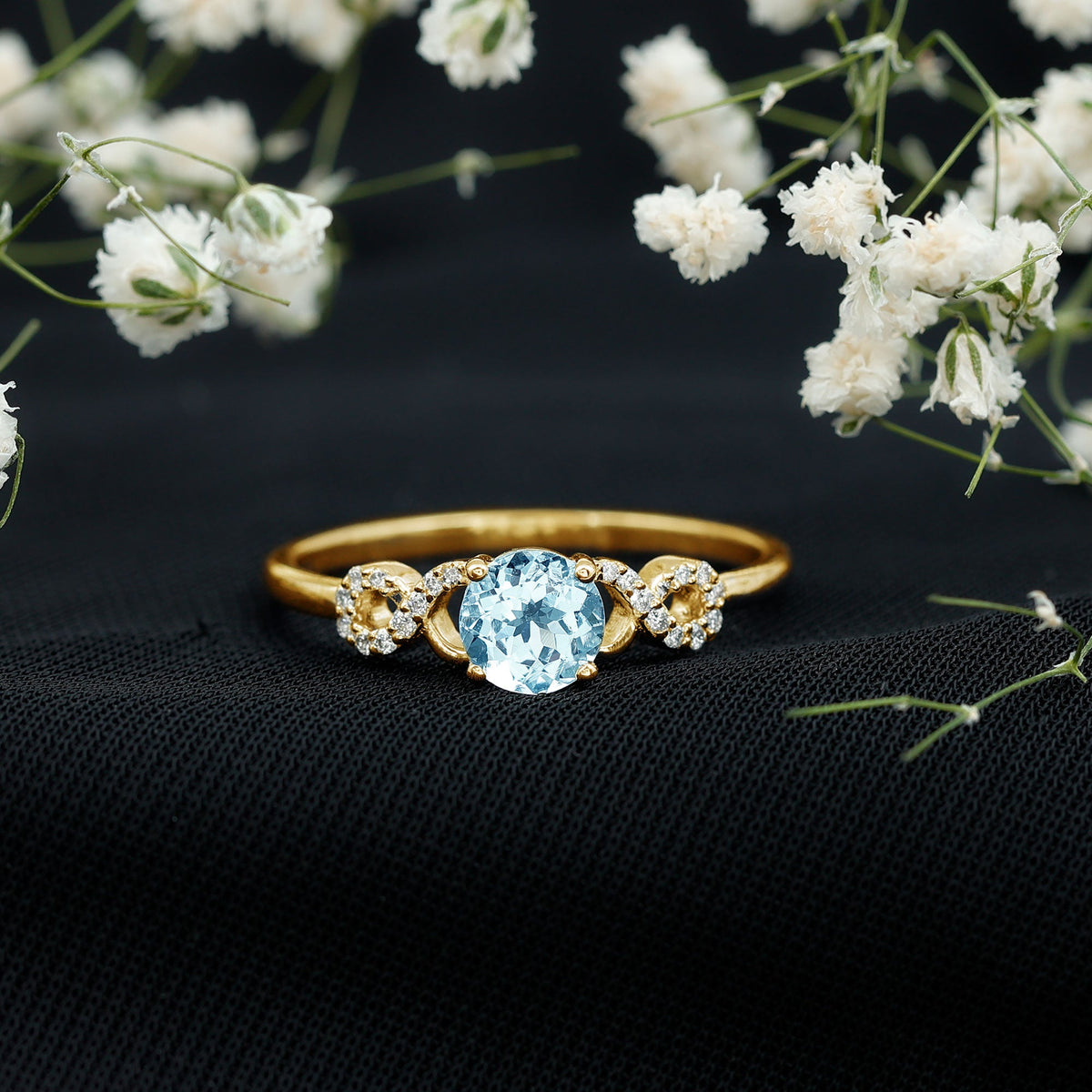Round aquamarine and diamond infinity engagement ring by Rosec Jewels featuring a delicate band and sparkling stones.