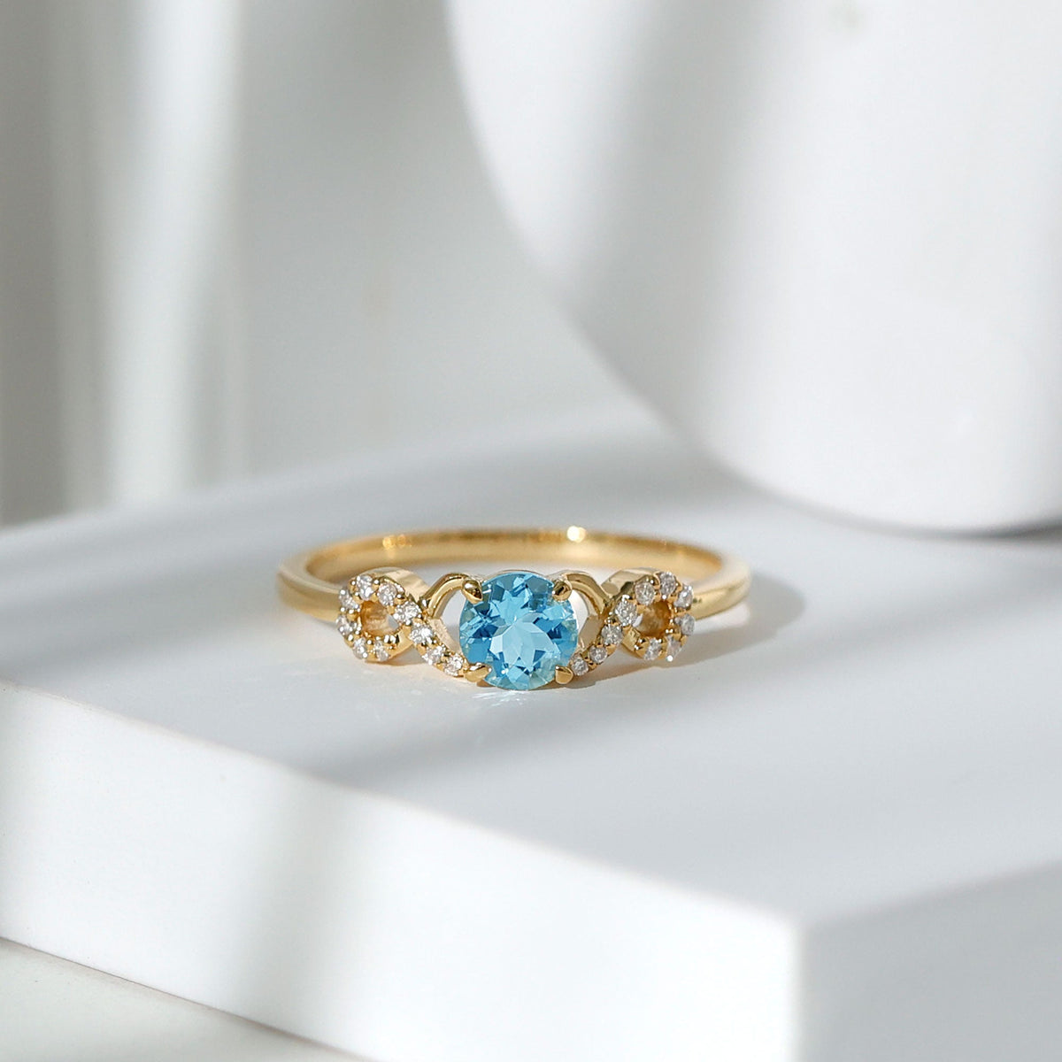 Round aquamarine and diamond infinity engagement ring by Rosec Jewels, featuring a sleek round shape and sparkling gemstones.