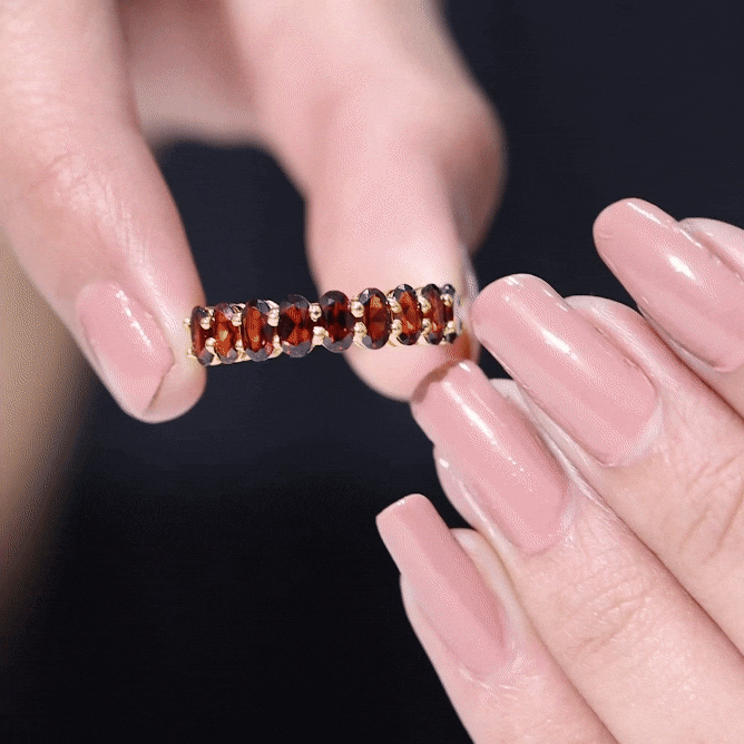 Genuine oval-shaped garnet half eternity ring by Rosec Jewels featuring a yellow gold band and sparkling gemstone accents.