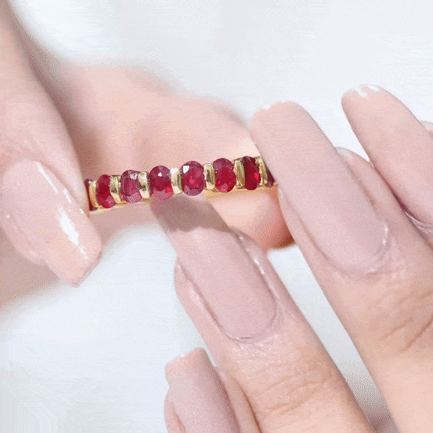 Oval cut created ruby half eternity ring in yellow gold with bar setting, featuring sparkling ruby stones around the band.