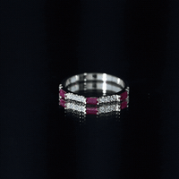 Rosec Jewels vintage eternity band featuring baguette cut lab-grown ruby and diamond accents, shown on a yellow background.