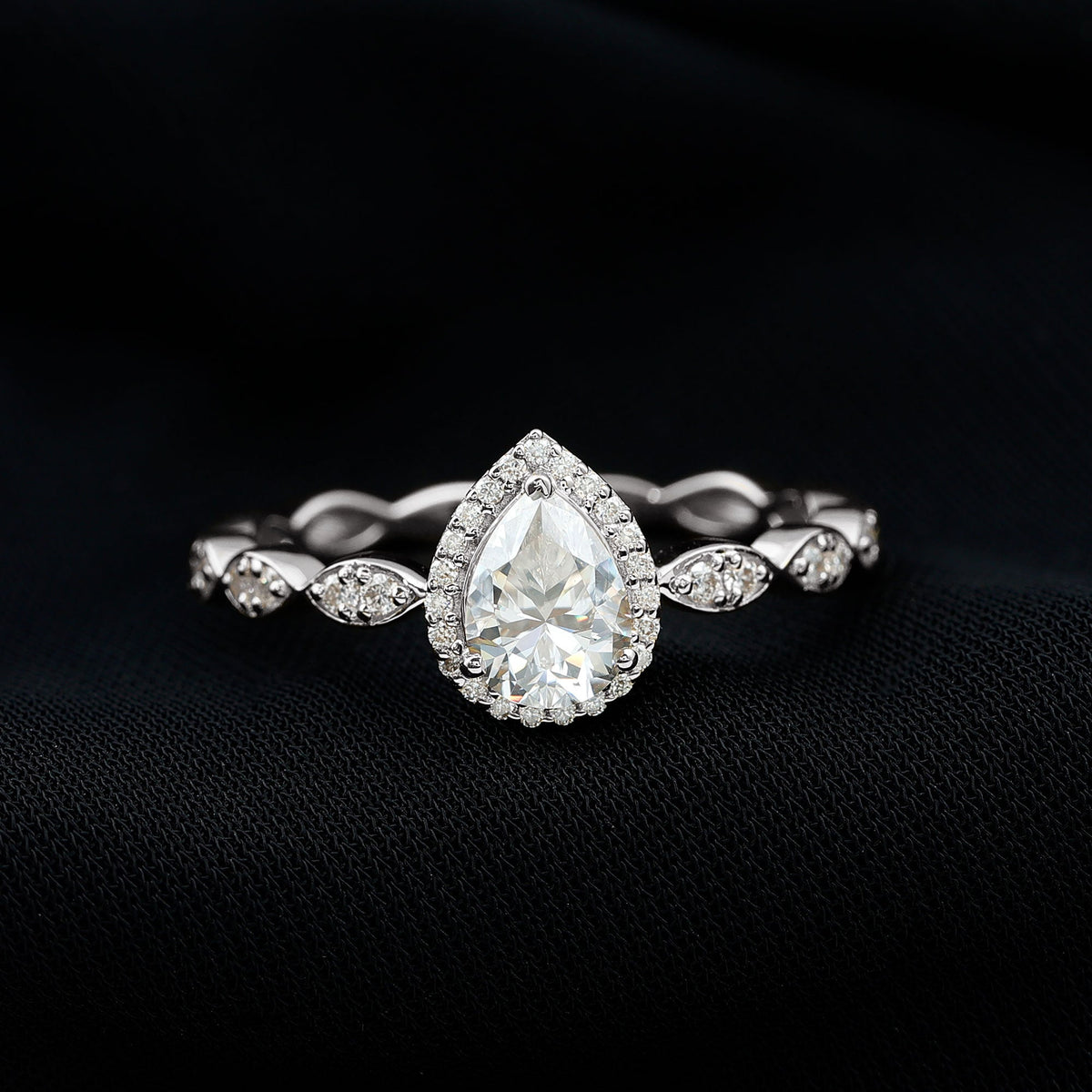 Moissanite teardrop engagement ring with scalloped shank from Rosec Jewels, featuring a sparkling central stone and intricate band detail.