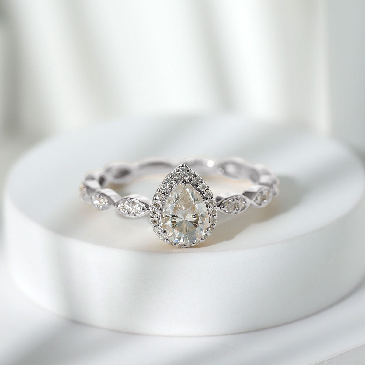 Moissanite teardrop engagement ring with scalloped shank by Rosec Jewels, showcasing the sparkling gemstone and intricate band design.