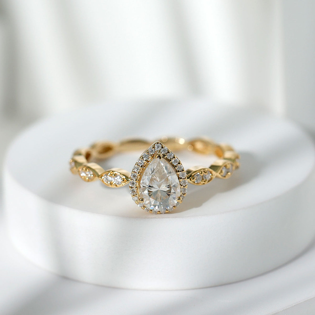 Moissanite teardrop engagement ring with scalloped shank from Rosec Jewels, showcasing sparkling gemstone and intricate band detail.