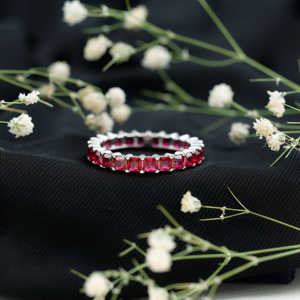 Rosec Jewels princess cut lab-grown ruby eternity wedding band for women, featuring sparkling ruby gemstones in a continuous circle of rings.