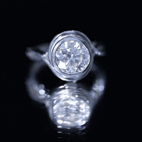 White certified moissanite bezel set engagement ring with crossover shank by Rosec Jewels, showcasing intricate band design.