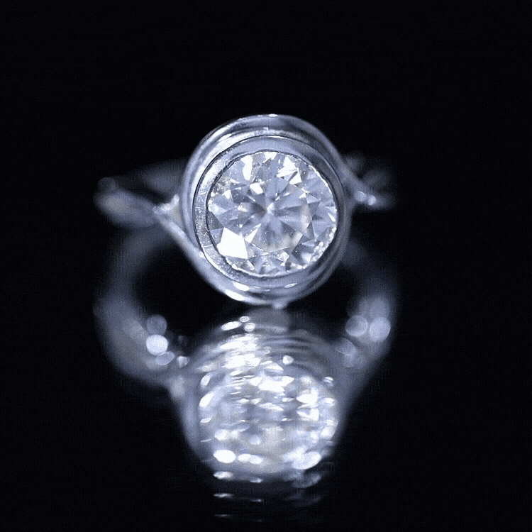 Yellow gold moissanite engagement ring with bezel setting and crossover shank by Rosec Jewels, showcasing sparkling gemstone and elegant design.
