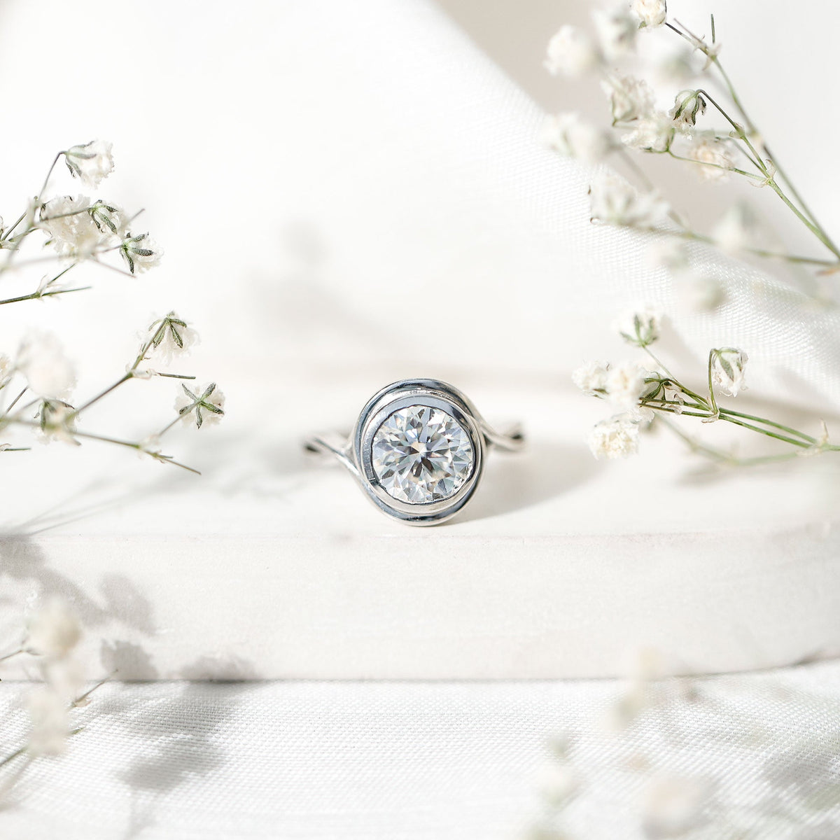 Certified Moissanite engagement ring with bezel setting and crossover shank by Rosec Jewels, showcasing sparkling center stone and sleek design.