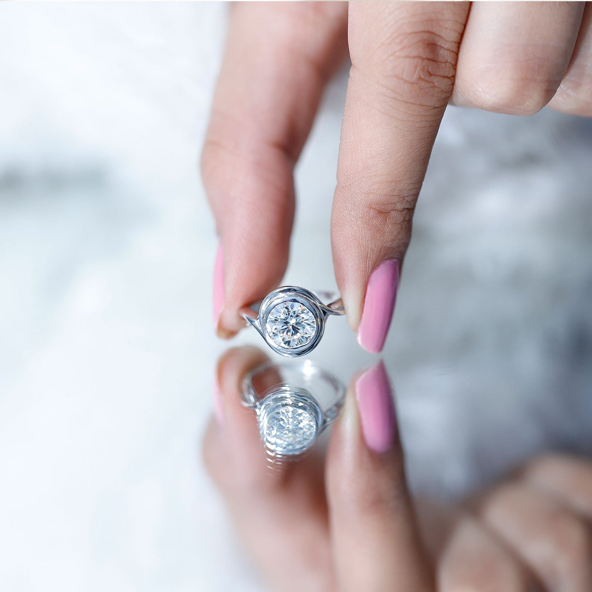 Rosec Jewels certified moissanite engagement ring with bezel setting and crossover shank, showcasing sparkling center stone and elegant design.