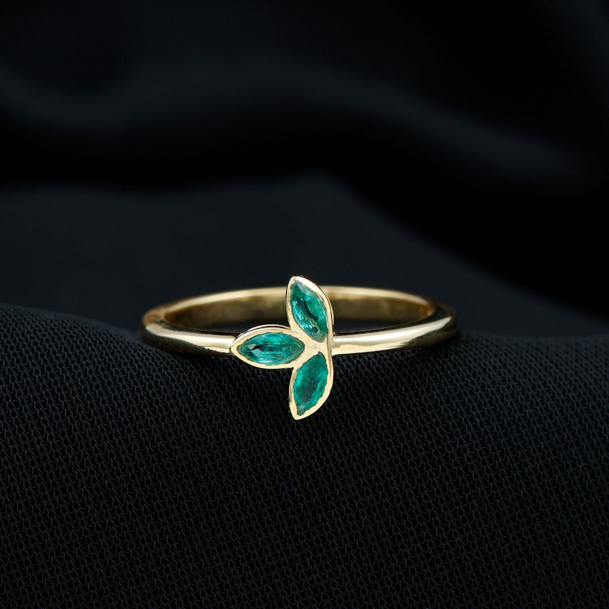 Marquise cut emerald leaf promise ring in bezel setting, showcasing intricate leaf design and sparkling green gemstone.
