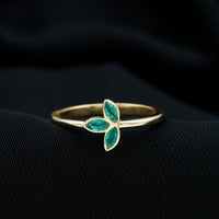 Marquise cut emerald leaf promise ring in bezel setting, showcasing intricate leaf design and sparkling green gemstone.