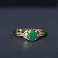 Oval cut emerald solitaire engagement ring with bow design by Rosec Jewels, showcasing the elegant green gemstone and intricate band details.