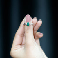 Oval cut emerald solitaire engagement ring with bow design by Rosec Jewels, featuring a central green emerald gemstone.