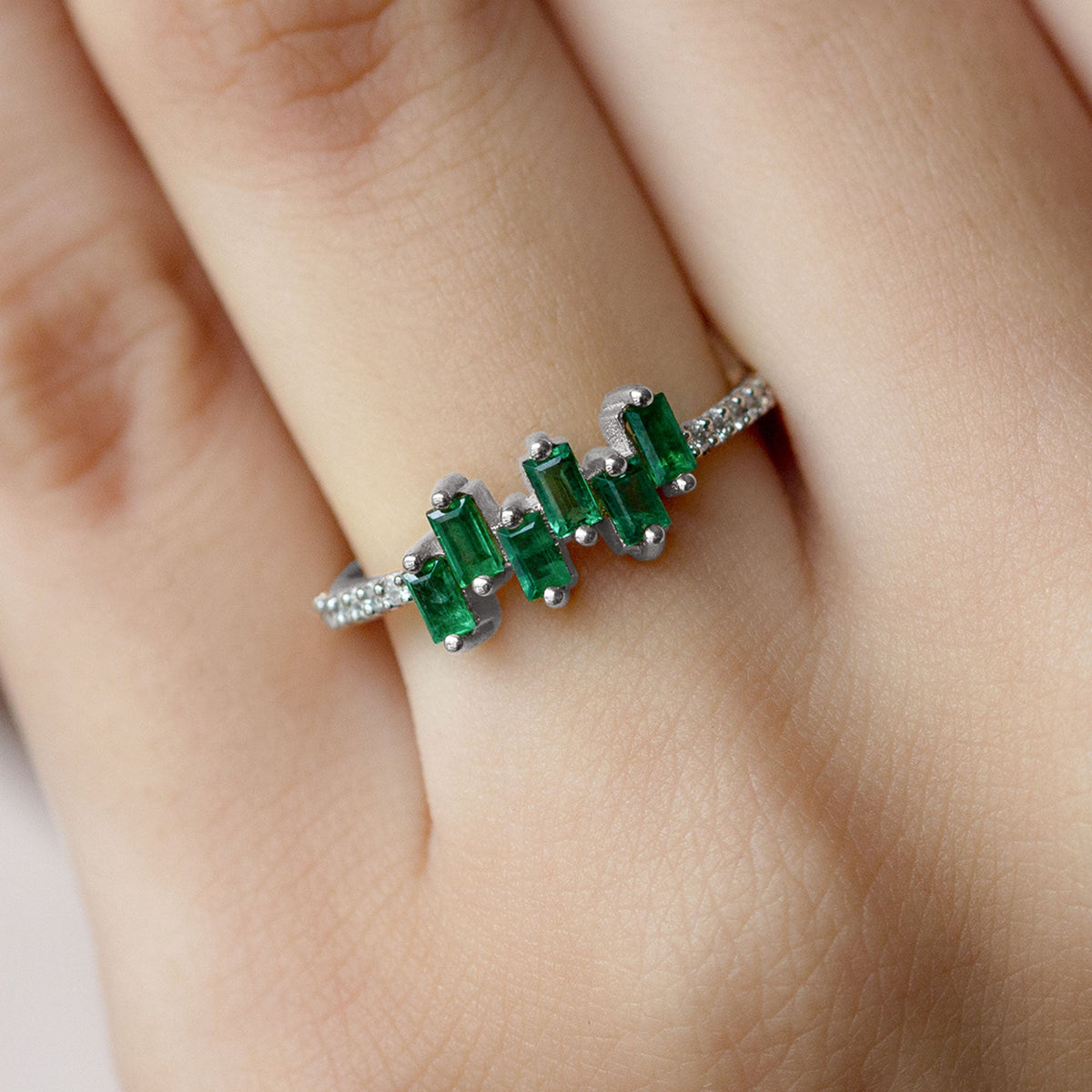 Baguette cut emerald promise ring with diamond side stones from Rosec Jewels, showcasing the elegant ring design and sparkling gemstones.