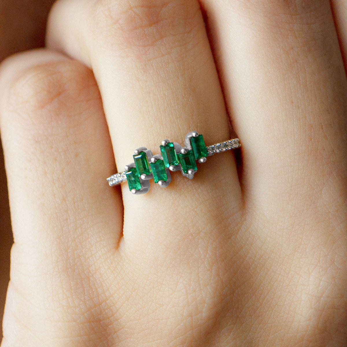 Rosec Jewels emerald promise ring featuring a baguette-cut emerald center stone with diamond side stones on a silver band.