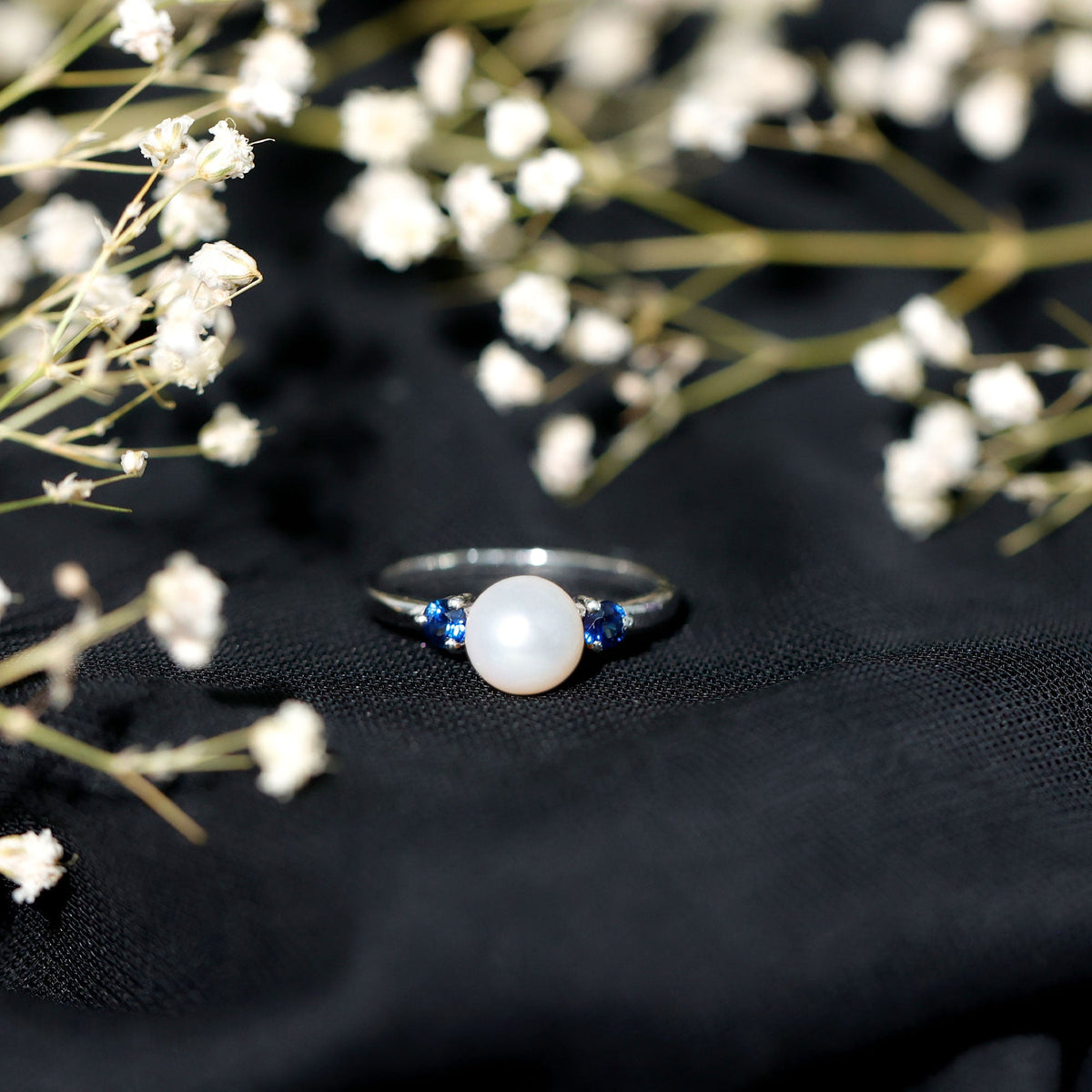 Cultured freshwater pearl engagement ring with blue sapphire accent, featuring a delicate band and elegant design from Rosec Jewels.