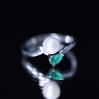 Cultured freshwater pearl and emerald Toi Et Moi promise ring by Rosec Jewels featuring two intertwined gemstones on a silver band.