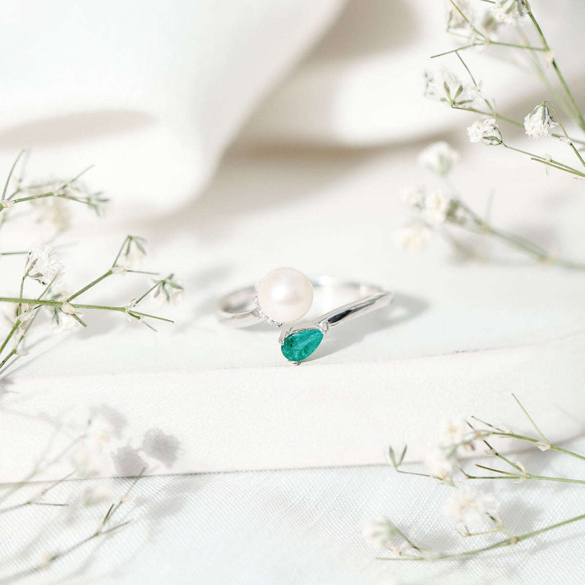 Cultured freshwater pearl and emerald toi et moi promise ring by Rosec Jewels, featuring a pearl and emerald set on a silver band.