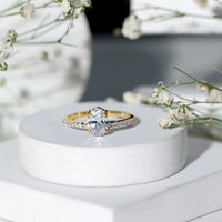 Oval cut zircon solitaire engagement ring with side stones in a silver setting, featuring a 1.2 carat center stone and intricate band details.