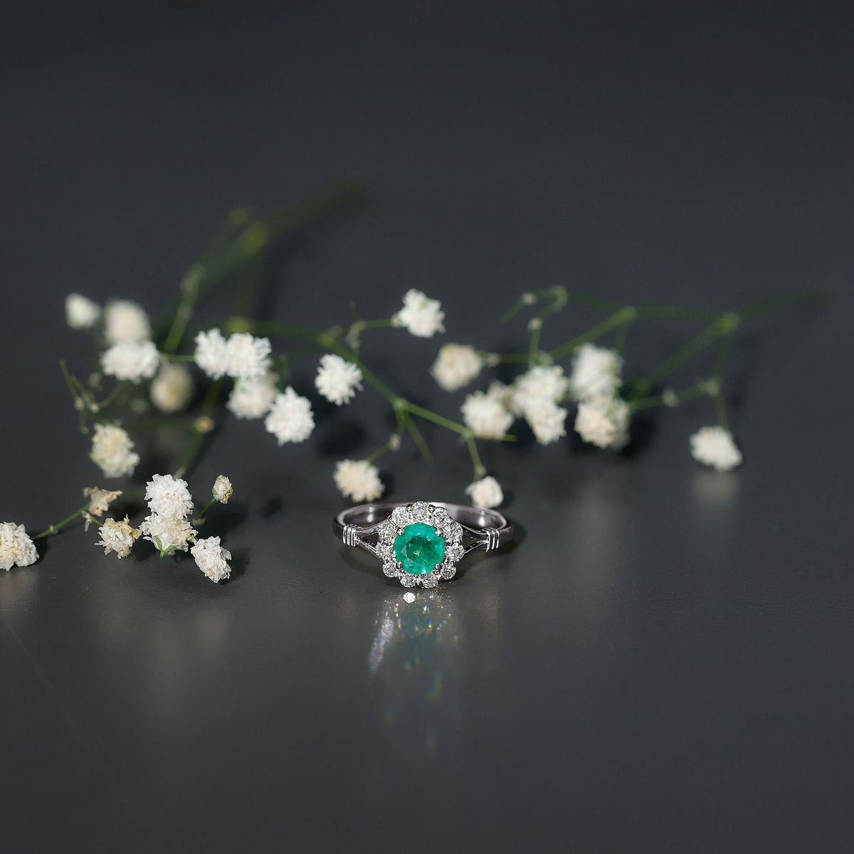 Emerald nature-inspired engagement ring by Rosec Jewels with diamond halo featuring intricate leaf design and sparkling gemstones.