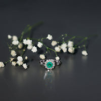 Emerald nature-inspired engagement ring by Rosec Jewels with diamond halo featuring intricate leaf design and sparkling gemstones.