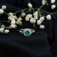 Emerald nature-inspired engagement ring with diamond halo by Rosec Jewels, showcasing intricate design and sparkling gemstones.