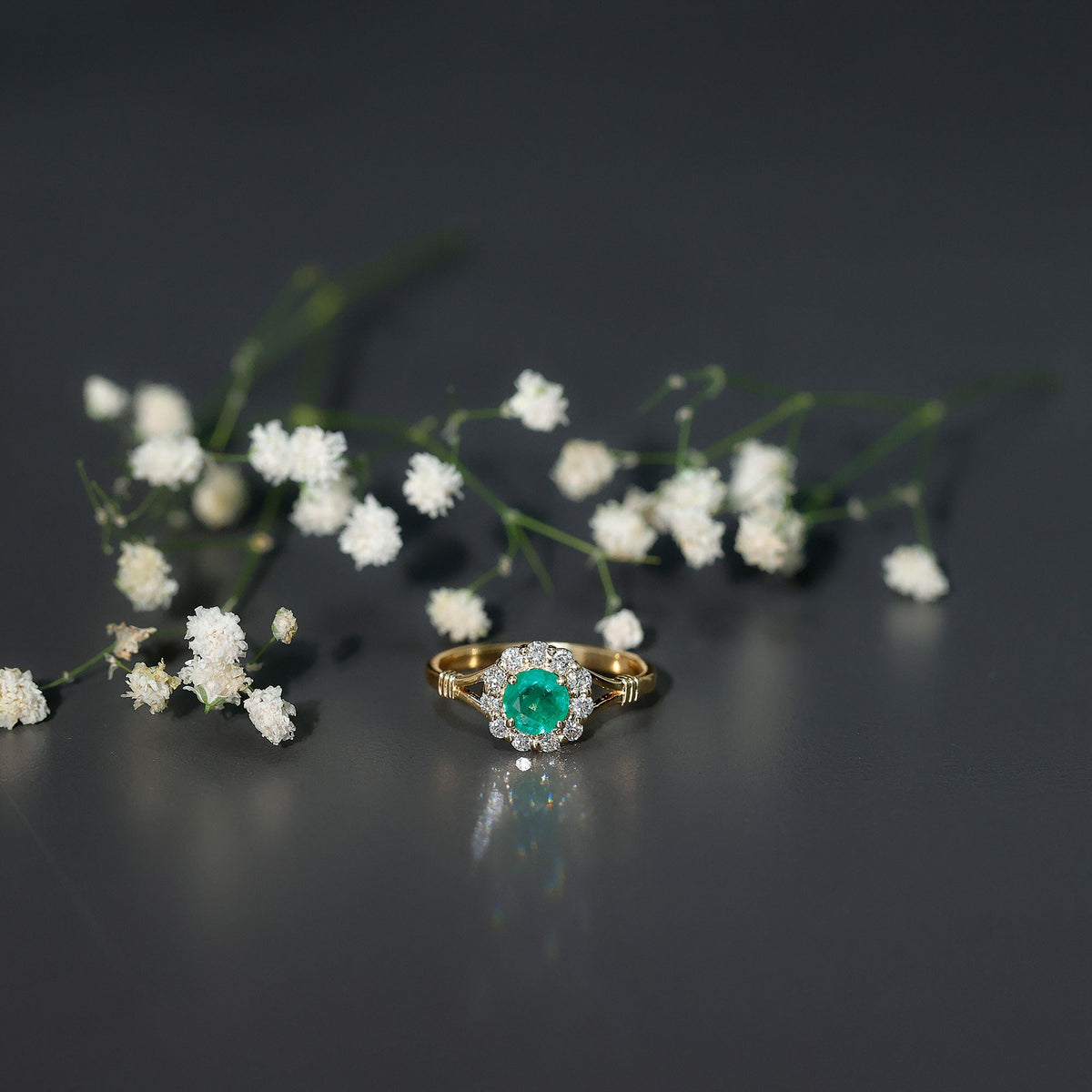 Emerald nature-inspired engagement ring with diamond halo, featuring intricate silver band design by Rosec Jewels.