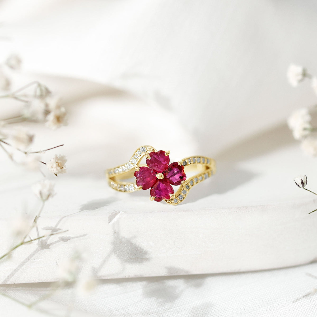 Real ruby flower engagement ring with diamond split shank featuring a central ruby flower and sparkling diamonds on a gold band.
