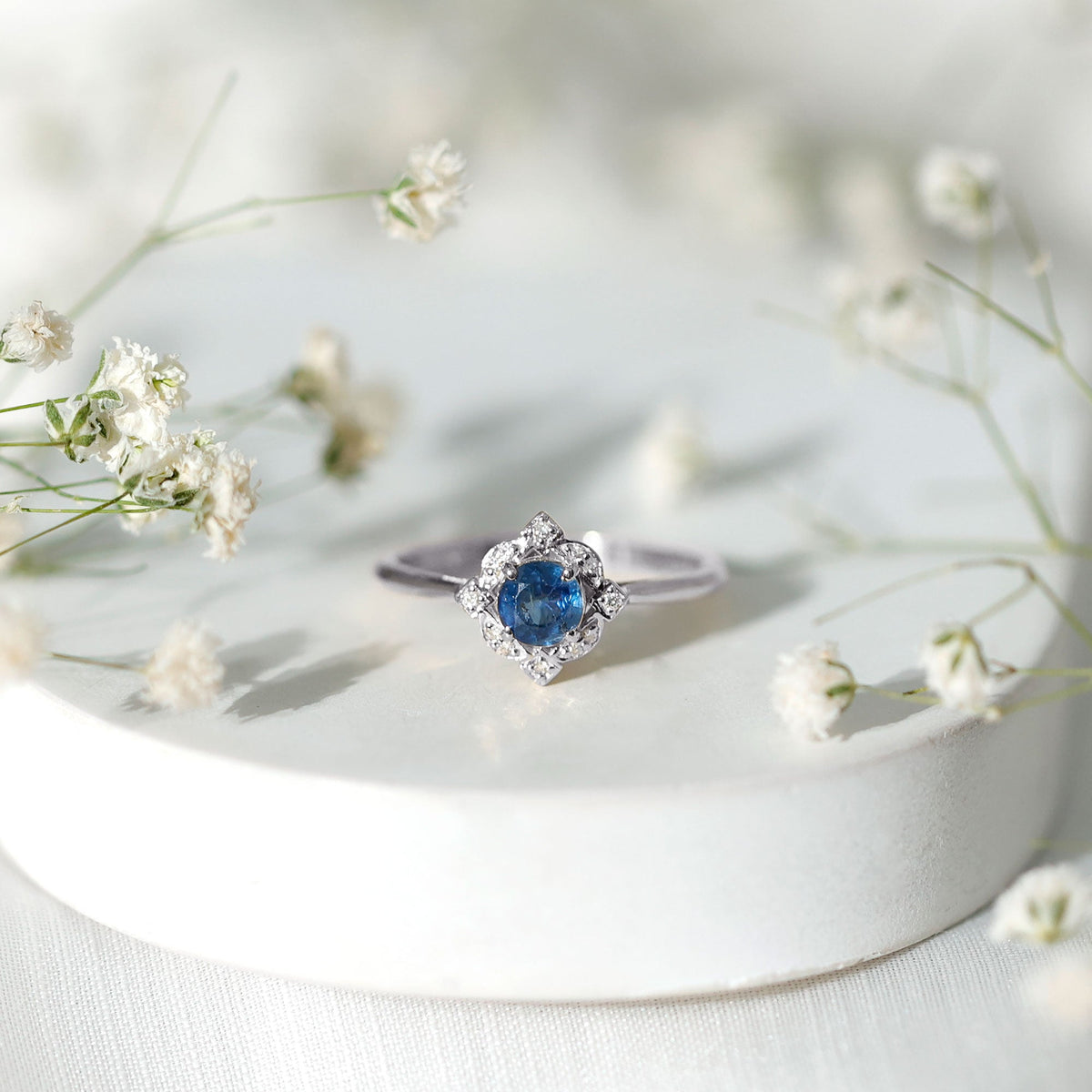 Vintage style 0.9 carat blue sapphire engagement ring with diamond halo by Rosec Jewels, featuring intricate metalwork and sparkling stones.
