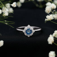 Vintage-style 0.9 carat blue sapphire engagement ring with diamond halo by Rosec Jewels, featuring intricate metalwork and sparkling stones.